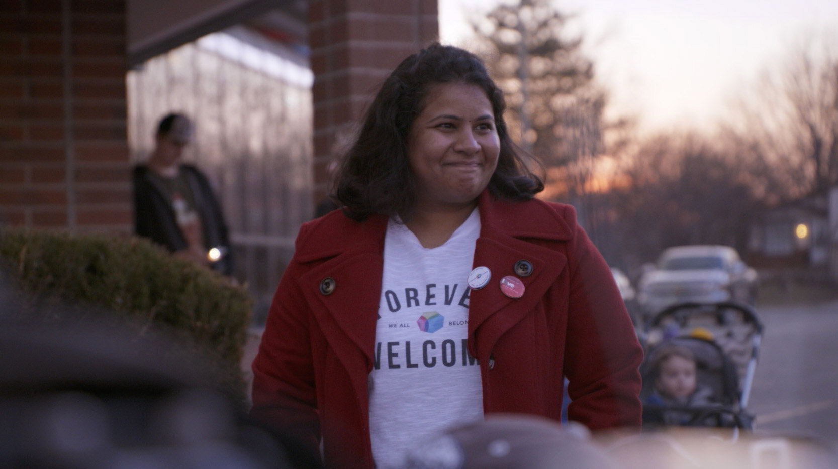 Film still of woman standing outside looking off camera with a gentle smile